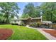 Charming one-story home with a landscaped yard, wooden porch, and a welcoming entrance surrounded by lush greenery at 2020 New Kemp Rd, Marietta, GA 30066
