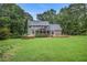 View of backyard featuring screened porch and stone patio with retaining wall and lush lawn at 386 Link Rd, Alpharetta, GA 30022