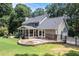 View of backyard featuring fire pit, stone patio with retaining wall, screened porch, and lush landscaping at 386 Link Rd, Alpharetta, GA 30022