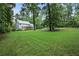 View of backyard featuring lush lawn and mature trees, with screened porch and stone patio visible at 386 Link Rd, Alpharetta, GA 30022