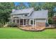 View of backyard featuring fire pit with stone patio, screened porch, and lush landscaping at 386 Link Rd, Alpharetta, GA 30022