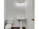 Bathroom with pedestal sink, toilet, dark wood floors and modern lighting at 11280 Brookhollow Trl, Alpharetta, GA 30022