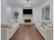 Bright living room featuring hardwood floors, a stone fireplace, and comfortable sofas at 11280 Brookhollow Trl, Alpharetta, GA 30022