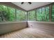 A sunroom with a ceiling fan and multiple windows overlooking lush, green trees at 11280 Brookhollow Trl, Alpharetta, GA 30022