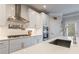 Modern kitchen with stainless steel range hood, gas cooktop, and undermount sink with tile backsplash at 4104 Townsend Ln, Dunwoody, GA 30346