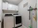 A functional laundry room with modern washer, dryer, storage cabinets, and cleaning supplies at 4104 Townsend Ln, Dunwoody, GA 30346