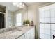 Bright bathroom featuring a granite countertop, white cabinetry, large mirror, and a window with blinds at 407 Yellowstone Dr, Powder Springs, GA 30127