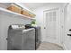 Well-lit laundry room featuring modern washer and dryer with open shelving and bright white door at 2435 Roxburgh Dr, Roswell, GA 30076