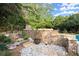 Backyard area with a stone wall, fireplace, gravel, and a step path, surrounded by greenery at 979 Pathview Ct, Dacula, GA 30019