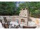 Backyard stone fireplace with adjacent patio furniture and retaining wall at 979 Pathview Ct, Dacula, GA 30019