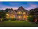 Beautiful brick home featuring manicured lawn, mature landscaping and charming architectural details at dusk at 979 Pathview Ct, Dacula, GA 30019