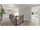 Hallway with carpeted floors, wood and wrought iron railings, and views into a windowed room at 979 Pathview Ct, Dacula, GA 30019