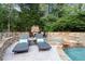 A backyard view of an in-ground pool with lounge furniture and an outdoor stone fireplace at 979 Pathview Ct, Dacula, GA 30019
