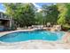 Inviting backyard pool with a stone patio, manicured garden, and cozy lounge furniture at 979 Pathview Ct, Dacula, GA 30019