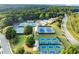 Overhead shot of the community tennis courts and swimming pool surrounded by lush, mature trees and manicured lawns at 979 Pathview Ct, Dacula, GA 30019