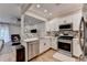 Well-lit kitchen featuring stainless steel appliances, white cabinets, and a view into the living area at 1203 Penhurst Way, Lawrenceville, GA 30043