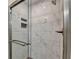 Close-up of a modern walk-in shower with marble-patterned tiling and sleek glass doors at 1203 Penhurst Way, Lawrenceville, GA 30043