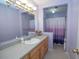 Well-lit bathroom featuring a spacious vanity, a bathtub with a shower and a calming violet color scheme at 155 Redspire Ln, Fayetteville, GA 30215