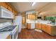 Open kitchen with wood cabinets, white appliances and views of the living room and dining area at 3318 Freedom Lndg, Kennesaw, GA 30144