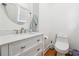 Powder room with a white vanity with silver pulls, a round mirror, and wood floors at 5535 Buck Hollow Dr, Alpharetta, GA 30005
