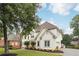 Angle view of a white home with manicured lawn, brick cottage, and mature trees at 5535 Buck Hollow Dr, Alpharetta, GA 30005