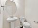 Powder room with a pedestal sink, round mirror, and modern fixtures at 728 Lorimore Pass, Canton, GA 30115
