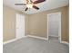 Cozy bedroom featuring beige walls, ceiling fan and gray carpet, plus an attached closet for easy storage at 728 Lorimore Pass, Canton, GA 30115