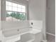 Bright bathroom with white tiled tub, shower and window for natural lighting at 3885 Riverview Chase Blf, Ellenwood, GA 30294