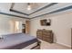 Well-lit bedroom with a trey ceiling, carpet floors, and a dresser at 4235 Crestwood Bend Cir, Buford, GA 30518