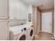 Bright laundry room with white cabinets, neutral walls, and modern washer and dryer at 4235 Crestwood Bend Cir, Buford, GA 30518