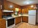 Cozy kitchen featuring wood cabinets, gas range, and tile flooring at 1791 Fairview Sw Dr, Austell, GA 30106