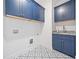 Laundry room showcasing striking patterned floors, blue cabinetry, sink, granite countertop, and modern fixtures at 2477 Bobbie Dr, Marietta, GA 30066
