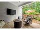 Outdoor patio featuring a stone floor, mounted TV, comfortable seating, and serene wooded view at 124 Calder Dr, Alpharetta, GA 30009