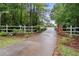 Gated driveway entrance with a charming white fence and lush greenery at 1368 Tommy Lee Cook Rd, Palmetto, GA 30268
