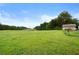 Vast grassy field with a small storage shed and distant trees at 1368 Tommy Lee Cook Rd, Palmetto, GA 30268