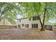 View of the back of the house with a fenced backyard, large tree and leaves at 10795 Glenbarr Dr, Johns Creek, GA 30097
