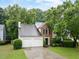 Brick and siding home with a well-maintained lawn, mature trees, and a two-car garage at 10795 Glenbarr Dr, Johns Creek, GA 30097