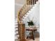 Close up of curved staircase with white and grey carpet, iron railings, and a side table with floral arrangement at 3639 Paper Mill Se Rd, Marietta, GA 30067