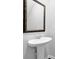 Stylish pedestal sink bathroom with a framed mirror and modern fixtures at 1998 Nuthatch Dr, Hoschton, GA 30548