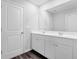 This bathroom features a double vanity with white cabinets, a large mirror, and wood floors at 1998 Nuthatch Dr, Hoschton, GA 30548