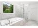 Bright bathroom featuring a soaking tub, glass shower, and views of the green landscape through the window at 281 Green Hill Rd, Atlanta, GA 30342