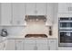 Close-up of kitchen showing stainless steel appliances, white cabinets, and tile backsplash at 4865 Chesterfield Ct, Suwanee, GA 30024
