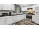 Modern kitchen featuring white cabinets, stainless steel appliances, dark countertops, and wood-style flooring at 2860 Jefferson St, Austell, GA 30106