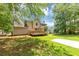 Home's back yard featuring deck, grassy lawn, mature trees and paved area at 4810 Habersham Se Way, Conyers, GA 30094