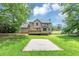 Home's back yard featuring deck, grassy lawn, mature trees and paved area at 4810 Habersham Se Way, Conyers, GA 30094
