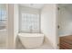 Bright and open bathroom with a modern soaking tub next to a large window at 153 Towey Trl, Woodstock, GA 30188