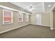 Spacious basement featuring neutral carpet, multiple windows, and a tray ceiling with ceiling fan at 240 Flowers Cove Ln, Lilburn, GA 30047