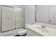 Well-lit bathroom with shower-tub combo featuring frosted glass sliding doors, and single sink at 240 Flowers Cove Ln, Lilburn, GA 30047