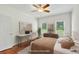 Bright staged bedroom features warm tones, hardwood floors, and natural light from the three windows at 240 Flowers Cove Ln, Lilburn, GA 30047
