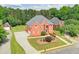 Aerial view of a brick two-story home with lush landscaping and a detached garage on a sunny day at 240 Flowers Cove Ln, Lilburn, GA 30047